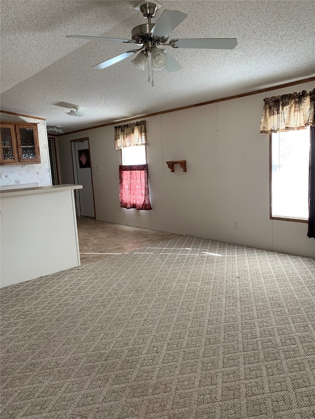 222 County Road 3331, Paradise, TX 76073 - unfurnished living room with light colored carpet, a ceiling fan, a textured ceiling, and ornamental molding