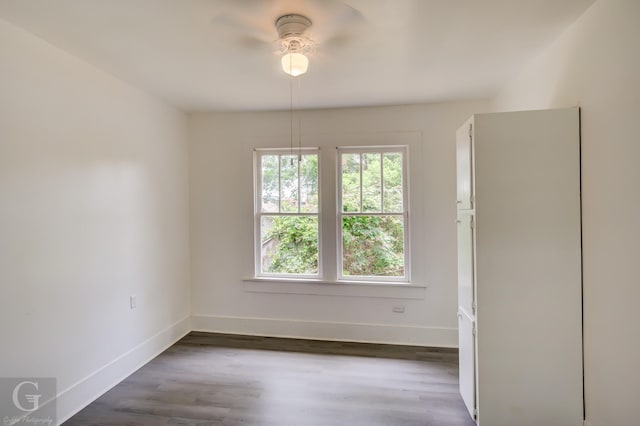 empty room with baseboards, dark wood finished floors, and ceiling fan