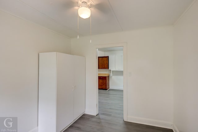 unfurnished room featuring baseboards, dark wood-type flooring, and ceiling fan