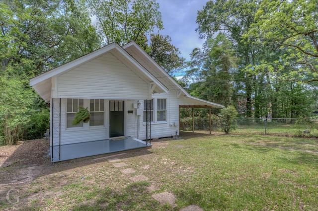 view of front of home featuring fence, an attached carport, and a front yard