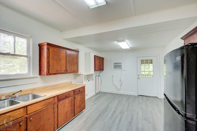 kitchen featuring a sink, freestanding refrigerator, light wood-style flooring, and a wealth of natural light