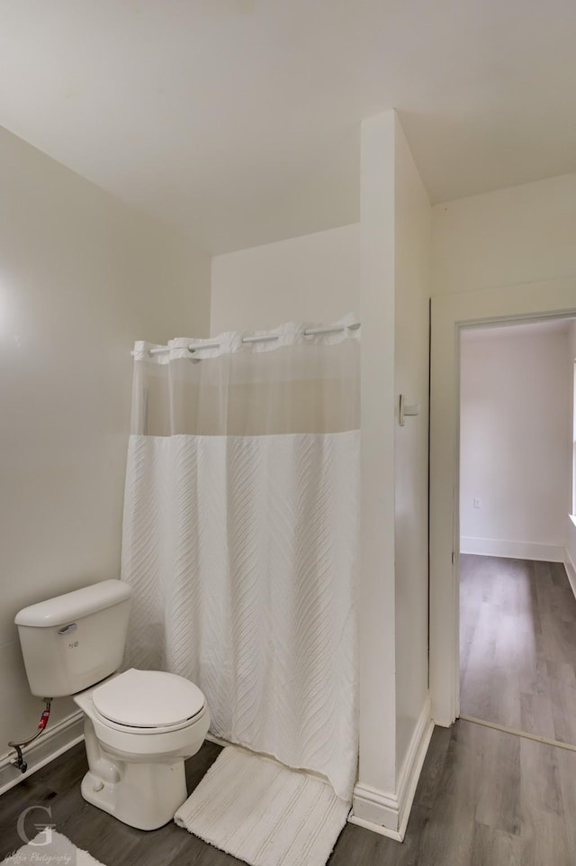 full bath with baseboards, wood finished floors, and toilet