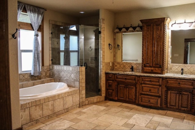 bathroom with a sink, stone tile floors, decorative backsplash, a bath, and a stall shower