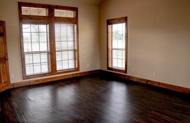 empty room with baseboards and dark wood-type flooring
