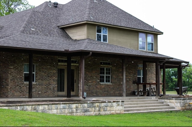 rear view of house featuring brick siding, a patio area, and roof with shingles