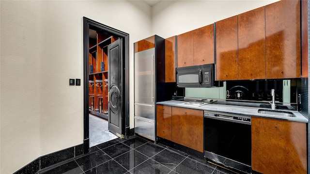 kitchen featuring a sink, a textured wall, black appliances, and brown cabinets