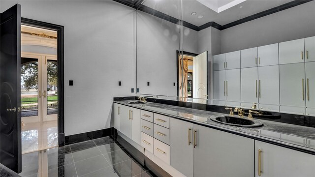 full bath featuring french doors, double vanity, baseboards, and a sink