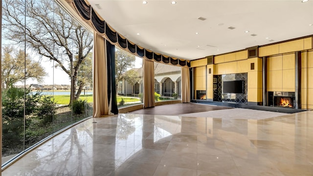 unfurnished living room with recessed lighting and a warm lit fireplace