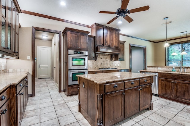 kitchen featuring backsplash, appliances with stainless steel finishes, a center island, a sink, and under cabinet range hood