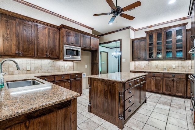 kitchen with decorative backsplash, a ceiling fan, crown molding, a sink, and stainless steel microwave