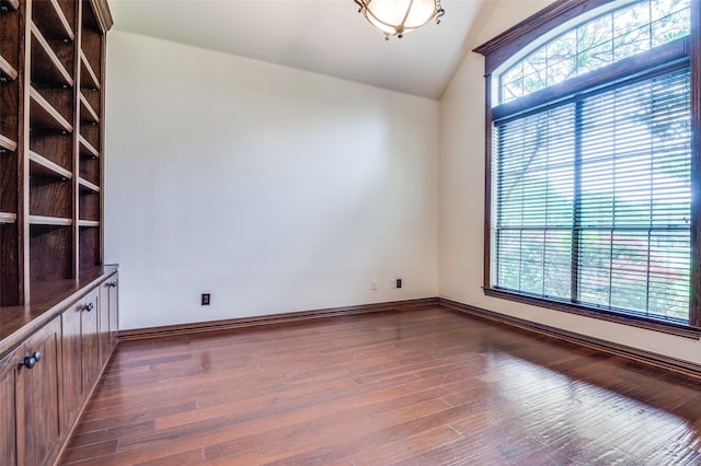 spare room featuring baseboards, vaulted ceiling, and dark wood finished floors