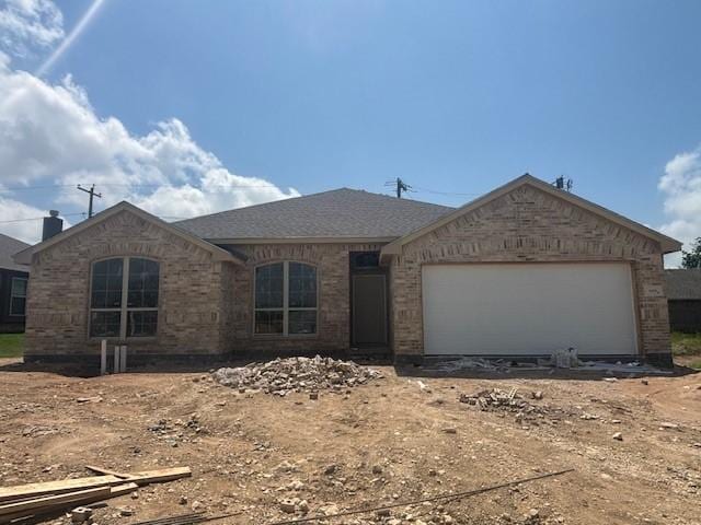view of front facade with an attached garage, driveway, and brick siding