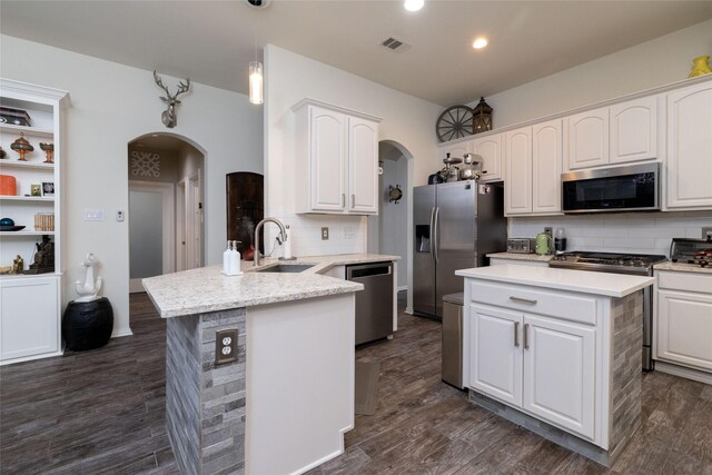 kitchen featuring arched walkways, appliances with stainless steel finishes, a sink, and a peninsula