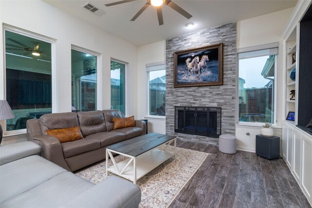 living room featuring ceiling fan, visible vents, dark wood-type flooring, and a fireplace
