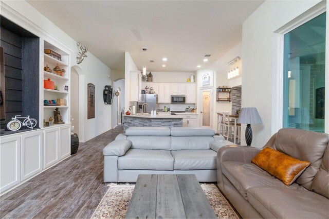 living room featuring arched walkways, recessed lighting, and wood finished floors