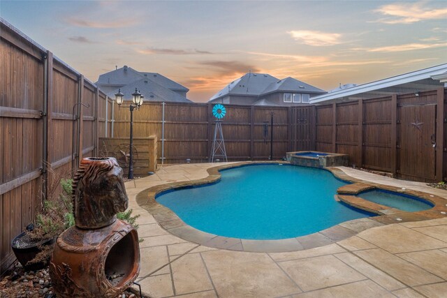 view of swimming pool featuring a patio, a fenced backyard, and a pool with connected hot tub