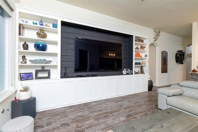 living area with arched walkways, baseboards, and wood finished floors
