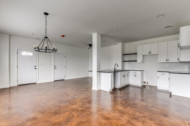 kitchen with finished concrete flooring, open floor plan, white cabinets, a sink, and ceiling fan with notable chandelier