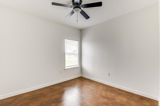 spare room featuring finished concrete floors, baseboards, and ceiling fan