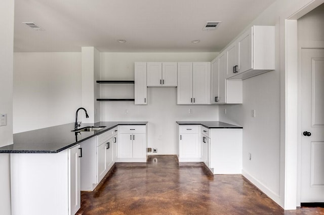 kitchen featuring dark countertops, visible vents, a sink, and finished concrete flooring