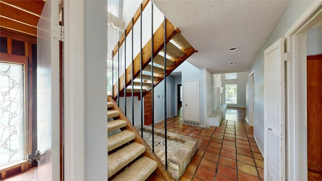 tiled foyer entrance with a textured ceiling and stairway