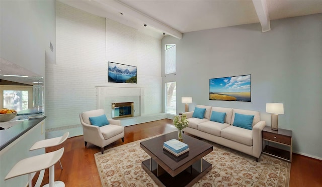 living area with a healthy amount of sunlight, beam ceiling, and wood finished floors