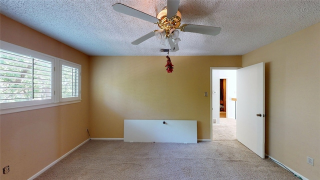 carpeted spare room with baseboards, a ceiling fan, and a textured ceiling