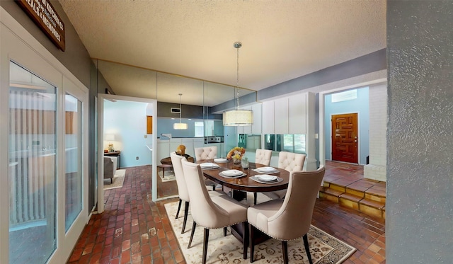 dining space featuring visible vents, a textured ceiling, and brick floor