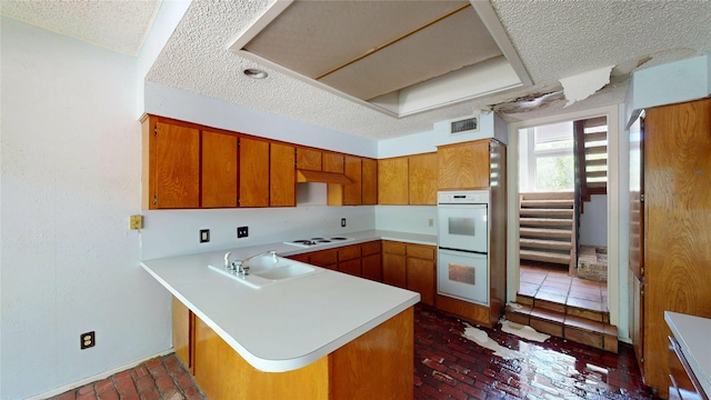 kitchen with brown cabinetry, a sink, brick floor, and white appliances