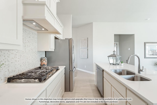 kitchen with light wood-style floors, light countertops, a sink, appliances with stainless steel finishes, and backsplash