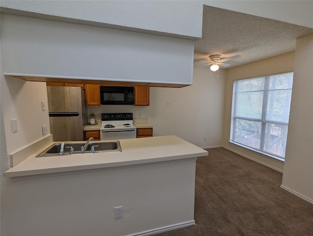 kitchen with brown cabinetry, black microwave, a sink, freestanding refrigerator, and white electric range oven