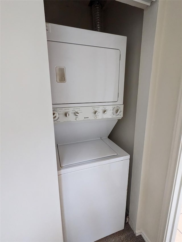 clothes washing area featuring baseboards, carpet, and stacked washing maching and dryer