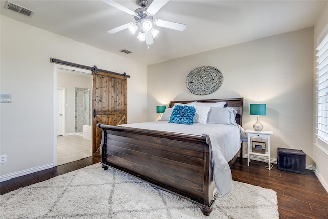 bedroom featuring visible vents, a barn door, wood-type flooring, and baseboards