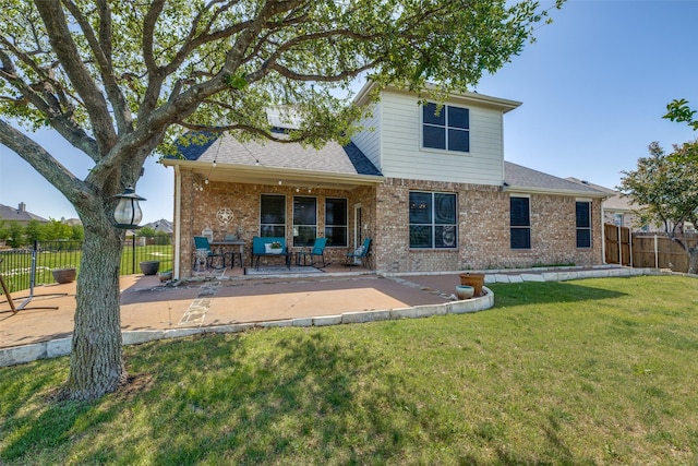 back of house with roof with shingles, brick siding, a fenced backyard, a lawn, and a patio