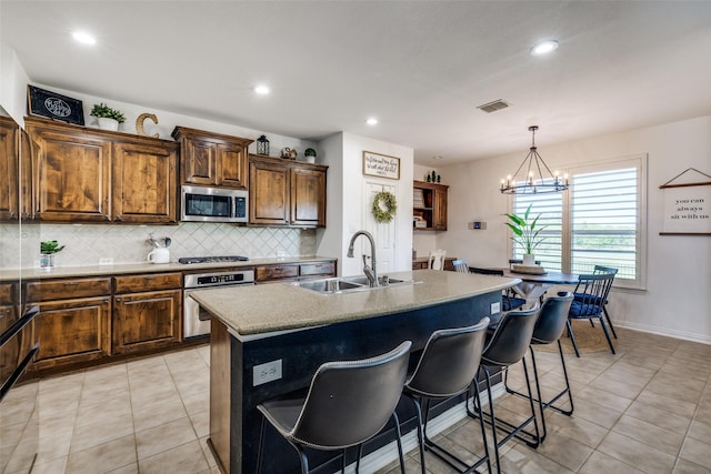 kitchen featuring visible vents, tasteful backsplash, a center island with sink, a sink, and stainless steel appliances