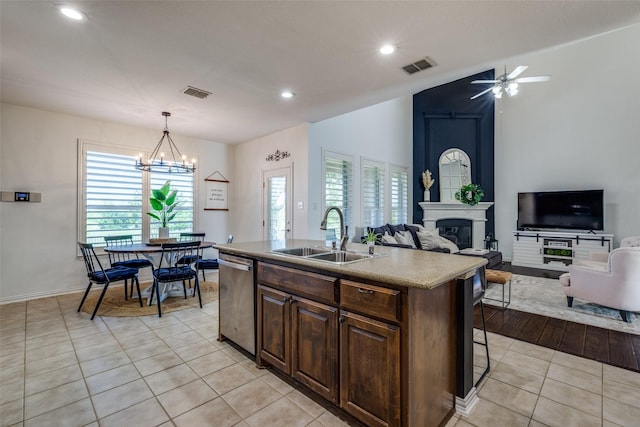 kitchen with stainless steel dishwasher, visible vents, a glass covered fireplace, and a sink