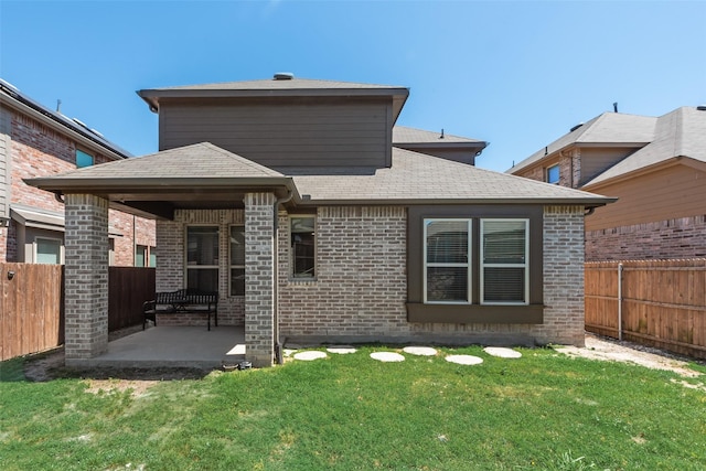 rear view of property featuring roof with shingles, a fenced backyard, a lawn, and a patio area
