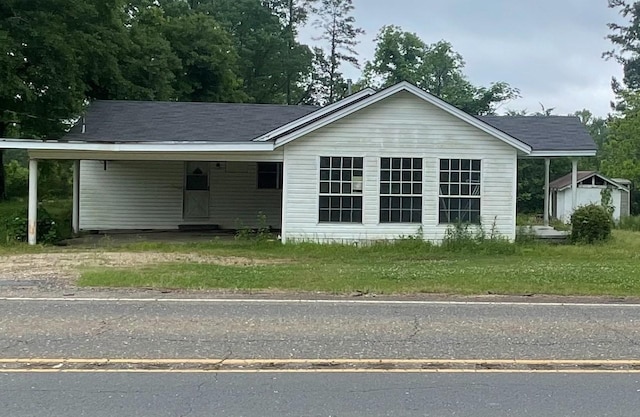 single story home featuring driveway, a storage unit, and a carport
