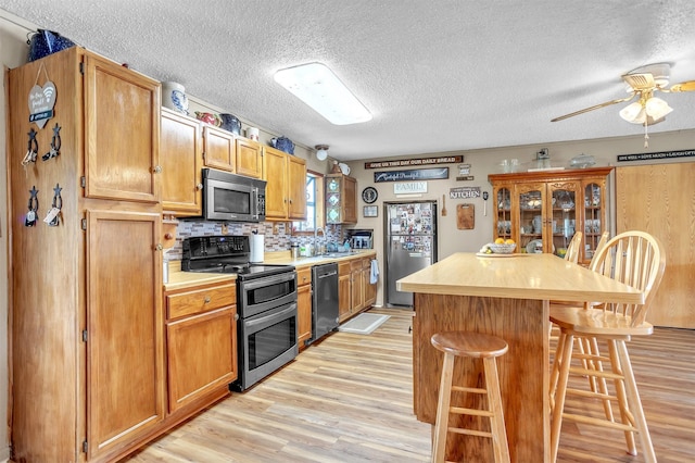kitchen with light countertops, light wood-style floors, stainless steel appliances, and a kitchen bar