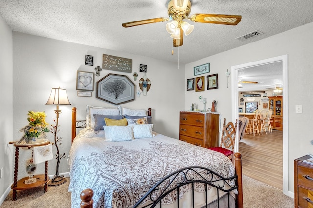 carpeted bedroom with visible vents, a ceiling fan, a textured ceiling, and baseboards
