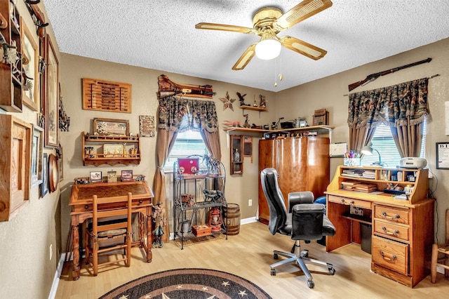 office featuring light wood-type flooring, a textured ceiling, and a wealth of natural light