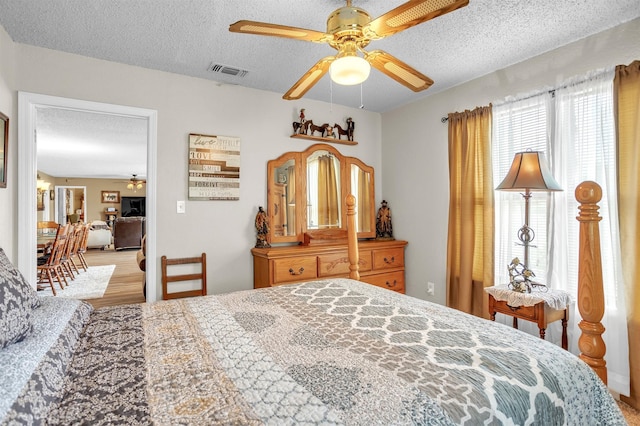 bedroom featuring wood finished floors, a ceiling fan, a textured ceiling, and visible vents