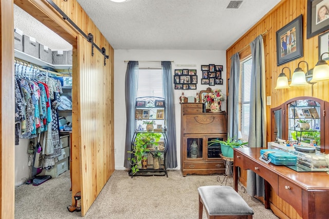 sitting room with carpet floors, wood walls, a barn door, and a wealth of natural light
