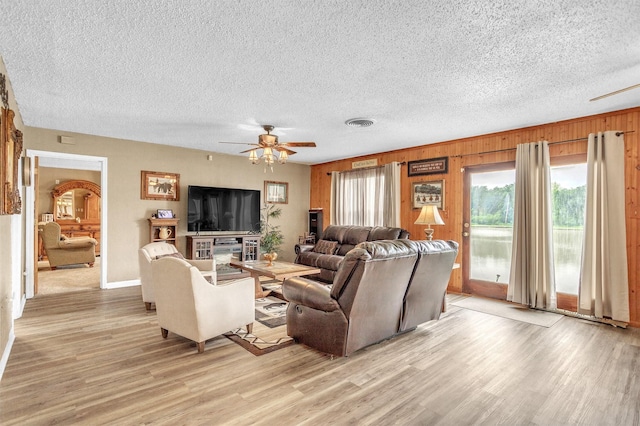living area with light wood-style floors, a ceiling fan, a textured ceiling, and a wealth of natural light