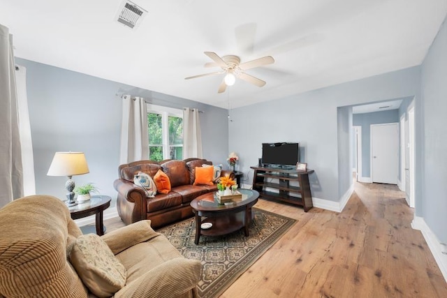 living area featuring baseboards, ceiling fan, visible vents, and light wood-style flooring