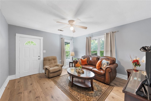 living area with visible vents, light wood finished floors, ceiling fan, and baseboards