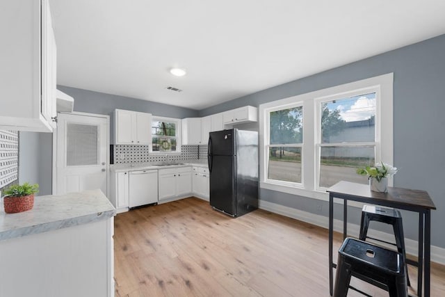 kitchen with visible vents, white dishwasher, light countertops, a sink, and freestanding refrigerator