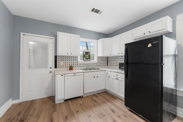 kitchen featuring freestanding refrigerator, white cabinets, a sink, and dishwasher