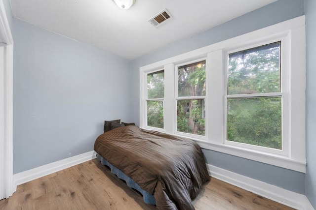 bedroom with baseboards, wood finished floors, and visible vents