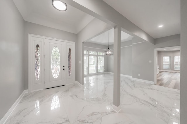 entryway with baseboards, an inviting chandelier, a wealth of natural light, and marble finish floor